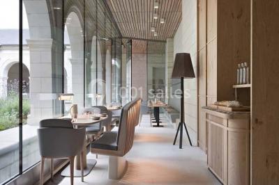 Chambre lumineuse avec lit double, mur beige capitonné, bureau minimaliste, chaise jaune et fenêtre à croisillons.