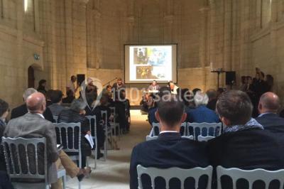 Chambre lumineuse avec lit double, mur beige capitonné, bureau minimaliste, chaise jaune et fenêtre à croisillons.