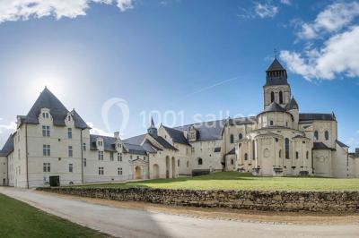 Chambre lumineuse avec lit double, mur beige capitonné, bureau minimaliste, chaise jaune et fenêtre à croisillons.