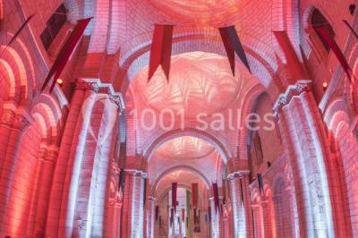 Chambre lumineuse avec lit double, mur beige capitonné, bureau minimaliste, chaise jaune et fenêtre à croisillons.
