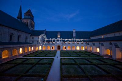 Chambre lumineuse avec lit double, mur beige capitonné, bureau minimaliste, chaise jaune et fenêtre à croisillons.