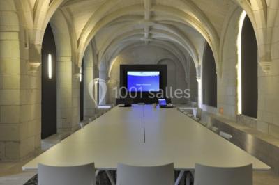 Chambre lumineuse avec lit double, mur beige capitonné, bureau minimaliste, chaise jaune et fenêtre à croisillons.