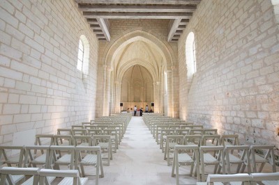 Chambre lumineuse avec lit double, mur beige capitonné, bureau minimaliste, chaise jaune et fenêtre à croisillons.