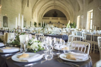 Chambre lumineuse avec lit double, mur beige capitonné, bureau minimaliste, chaise jaune et fenêtre à croisillons.