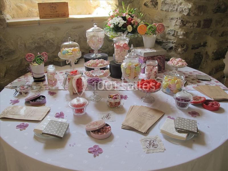 Table décorée avec des bonbonnières remplies de sucreries colorées, entourées de sachets et de décorations florales.