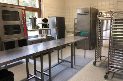 Miniature Location salle Guillon-les-Bains (Doubs) - Domaine Les Bains #25 Cuisine professionnelle équipée de plans de travail en inox, fours, étagères métalliques et carrelage mural blanc.