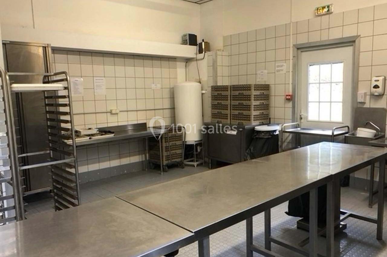 Cuisine professionnelle avec plans de travail en inox, étagères, chariots et équipements de rangement.