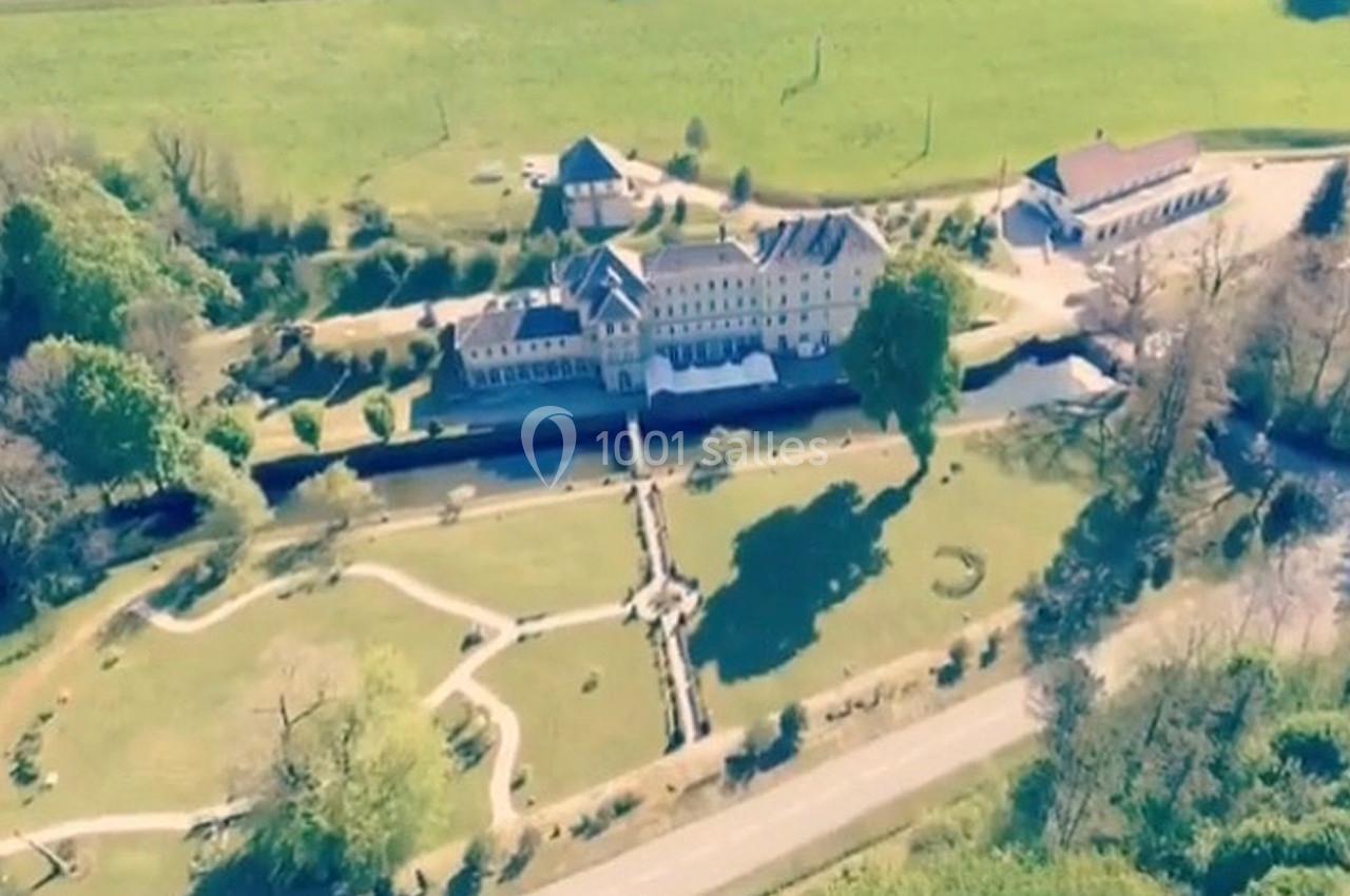 Vue aérienne d'un grand bâtiment historique entouré de jardins verdoyants et d'une route à proximité.