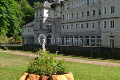 Miniature Location salle Guillon-les-Bains (Doubs) - Domaine Les Bains #13 Cuisine professionnelle équipée de plans de travail en inox, fours, étagères métalliques et carrelage mural blanc.