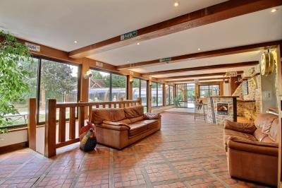 Salle de bain lumineuse avec baignoire encastrée sur estrade carrelée, poutres apparentes et grande fenêtre.