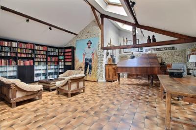 Salle de bain lumineuse avec baignoire encastrée sur estrade carrelée, poutres apparentes et grande fenêtre.