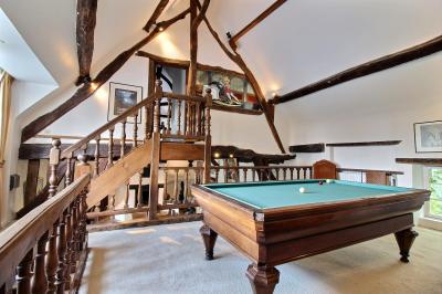 Salle de bain lumineuse avec baignoire encastrée sur estrade carrelée, poutres apparentes et grande fenêtre.