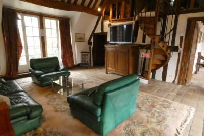 Salle de bain lumineuse avec baignoire encastrée sur estrade carrelée, poutres apparentes et grande fenêtre.