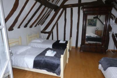 Salle de bain lumineuse avec baignoire encastrée sur estrade carrelée, poutres apparentes et grande fenêtre.