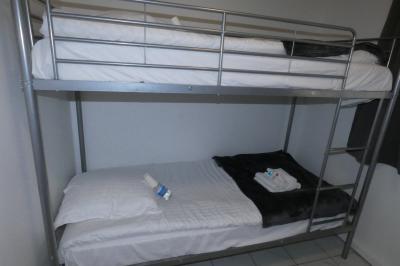 Salle de bain lumineuse avec baignoire encastrée sur estrade carrelée, poutres apparentes et grande fenêtre.