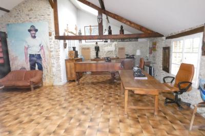 Salle de bain lumineuse avec baignoire encastrée sur estrade carrelée, poutres apparentes et grande fenêtre.