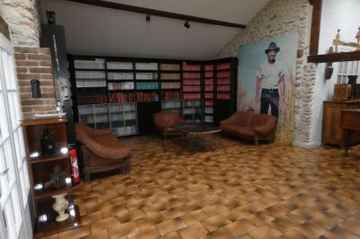 Salle de bain lumineuse avec baignoire encastrée sur estrade carrelée, poutres apparentes et grande fenêtre.