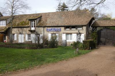 Salle de bain lumineuse avec baignoire encastrée sur estrade carrelée, poutres apparentes et grande fenêtre.