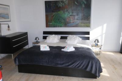 Salle de bain lumineuse avec baignoire encastrée sur estrade carrelée, poutres apparentes et grande fenêtre.