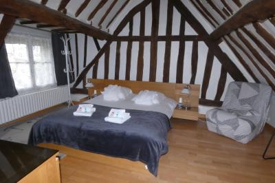 Salle de bain lumineuse avec baignoire encastrée sur estrade carrelée, poutres apparentes et grande fenêtre.