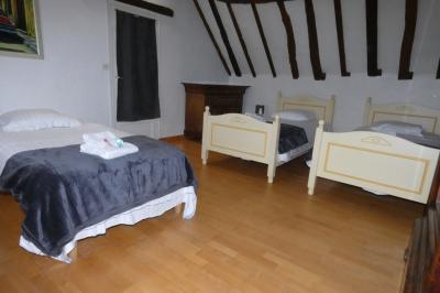 Salle de bain lumineuse avec baignoire encastrée sur estrade carrelée, poutres apparentes et grande fenêtre.