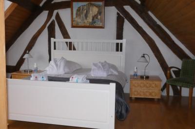 Salle de bain lumineuse avec baignoire encastrée sur estrade carrelée, poutres apparentes et grande fenêtre.