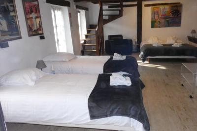 Salle de bain lumineuse avec baignoire encastrée sur estrade carrelée, poutres apparentes et grande fenêtre.