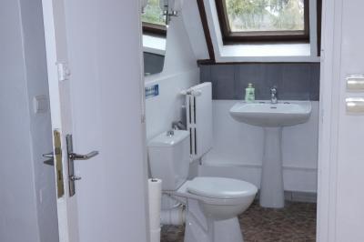 Salle de bain lumineuse avec baignoire encastrée sur estrade carrelée, poutres apparentes et grande fenêtre.