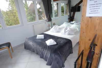 Salle de bain lumineuse avec baignoire encastrée sur estrade carrelée, poutres apparentes et grande fenêtre.