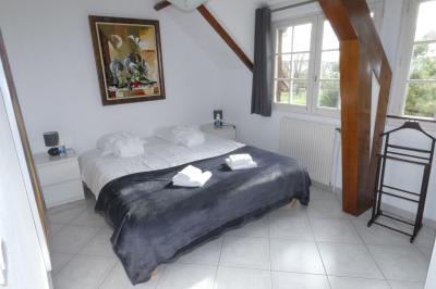 Salle de bain lumineuse avec baignoire encastrée sur estrade carrelée, poutres apparentes et grande fenêtre.