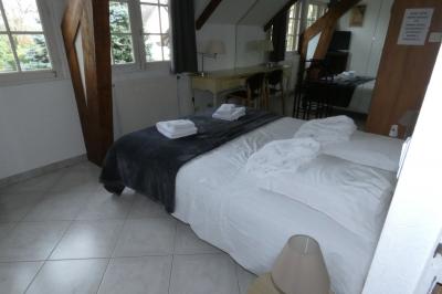 Salle de bain lumineuse avec baignoire encastrée sur estrade carrelée, poutres apparentes et grande fenêtre.