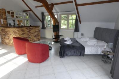 Salle de bain lumineuse avec baignoire encastrée sur estrade carrelée, poutres apparentes et grande fenêtre.