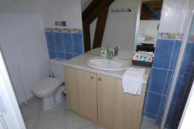 Salle de bain lumineuse avec baignoire encastrée sur estrade carrelée, poutres apparentes et grande fenêtre.