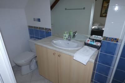 Salle de bain lumineuse avec baignoire encastrée sur estrade carrelée, poutres apparentes et grande fenêtre.