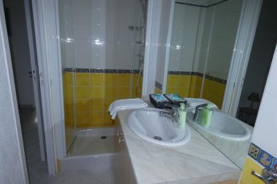 Salle de bain lumineuse avec baignoire encastrée sur estrade carrelée, poutres apparentes et grande fenêtre.