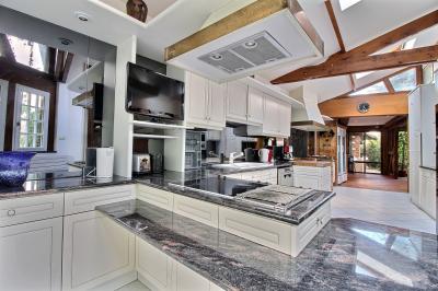 Salle de bain lumineuse avec baignoire encastrée sur estrade carrelée, poutres apparentes et grande fenêtre.