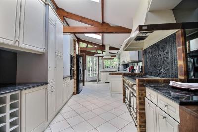 Salle de bain lumineuse avec baignoire encastrée sur estrade carrelée, poutres apparentes et grande fenêtre.