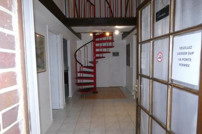 Salle de bain lumineuse avec baignoire encastrée sur estrade carrelée, poutres apparentes et grande fenêtre.