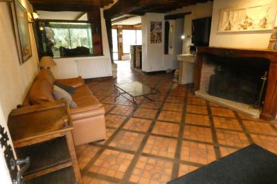Salle de bain lumineuse avec baignoire encastrée sur estrade carrelée, poutres apparentes et grande fenêtre.