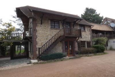 Salle de bain lumineuse avec baignoire encastrée sur estrade carrelée, poutres apparentes et grande fenêtre.