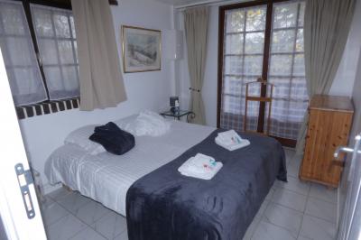 Salle de bain lumineuse avec baignoire encastrée sur estrade carrelée, poutres apparentes et grande fenêtre.