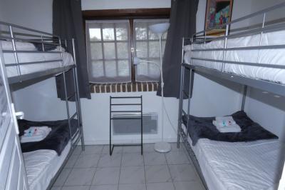 Salle de bain lumineuse avec baignoire encastrée sur estrade carrelée, poutres apparentes et grande fenêtre.