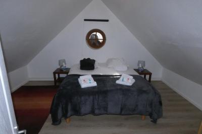 Salle de bain lumineuse avec baignoire encastrée sur estrade carrelée, poutres apparentes et grande fenêtre.