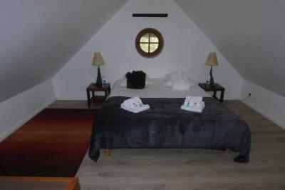 Salle de bain lumineuse avec baignoire encastrée sur estrade carrelée, poutres apparentes et grande fenêtre.