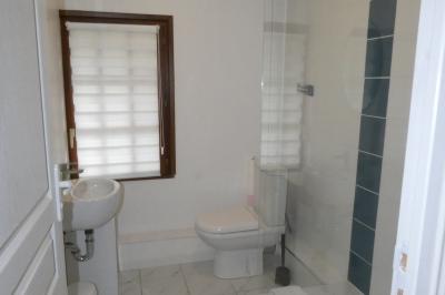 Salle de bain lumineuse avec baignoire encastrée sur estrade carrelée, poutres apparentes et grande fenêtre.