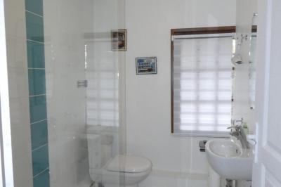 Salle de bain lumineuse avec baignoire encastrée sur estrade carrelée, poutres apparentes et grande fenêtre.