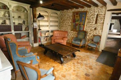 Salle de bain lumineuse avec baignoire encastrée sur estrade carrelée, poutres apparentes et grande fenêtre.