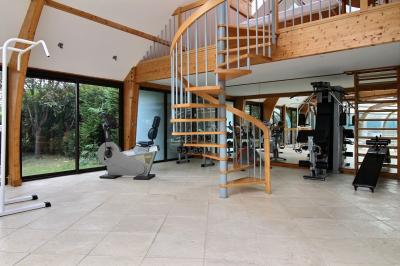 Salle de bain lumineuse avec baignoire encastrée sur estrade carrelée, poutres apparentes et grande fenêtre.