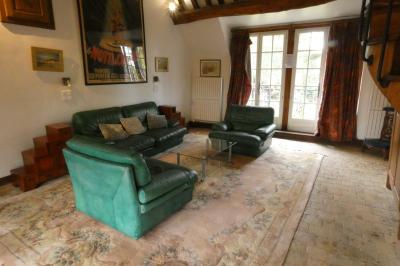 Salle de bain lumineuse avec baignoire encastrée sur estrade carrelée, poutres apparentes et grande fenêtre.