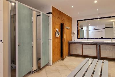 Salle de bain lumineuse avec baignoire encastrée sur estrade carrelée, poutres apparentes et grande fenêtre.